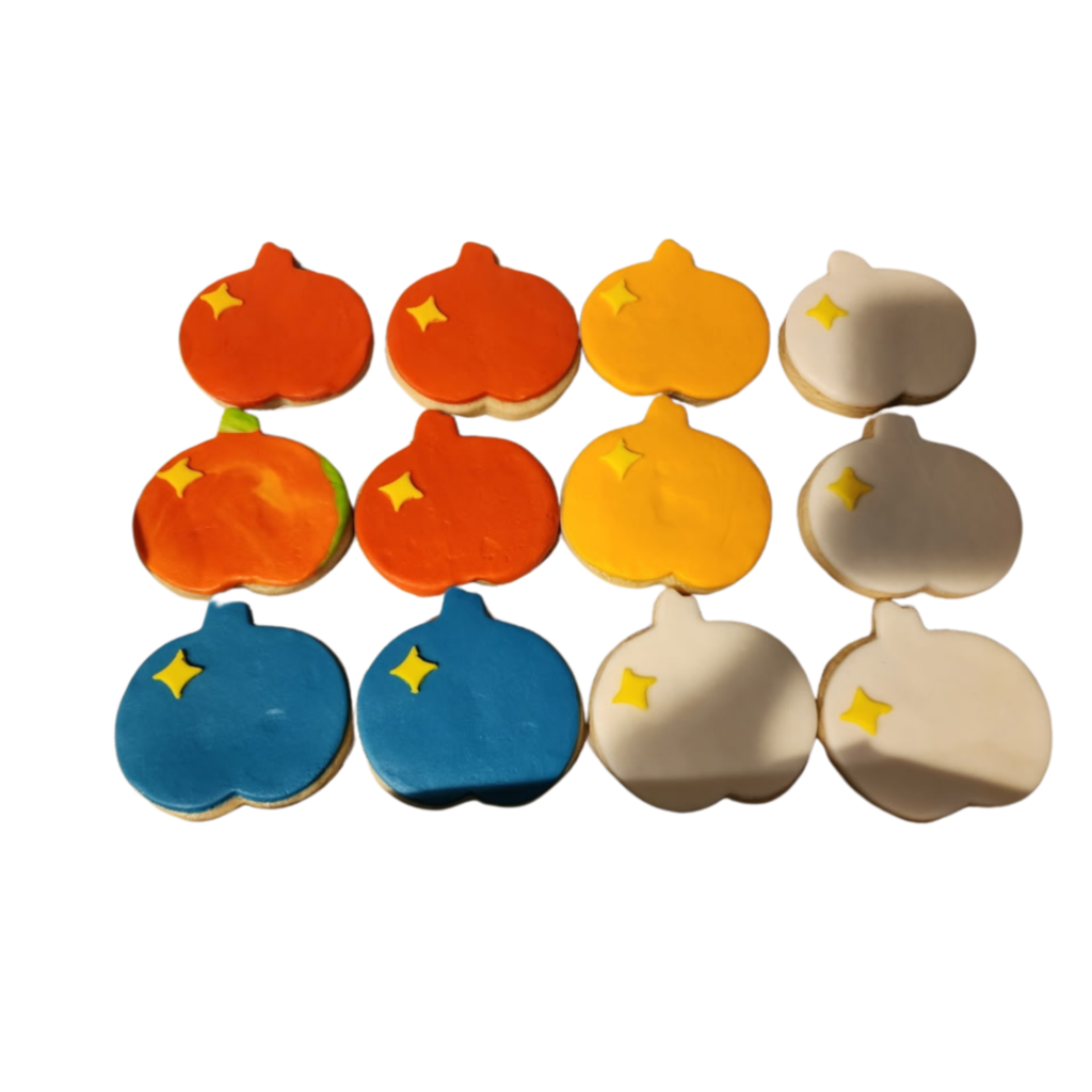 A set of seasonal sugar cookies featuring hand-piped royal icing designs of red apples and orange pumpkins.