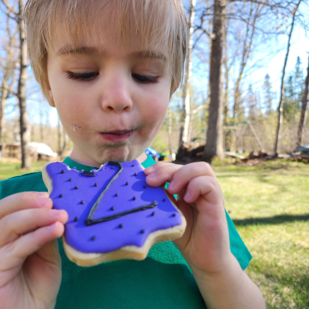 A young child enjoying a custom-decorated sugar cookie from Pioneer Spirit outdoors