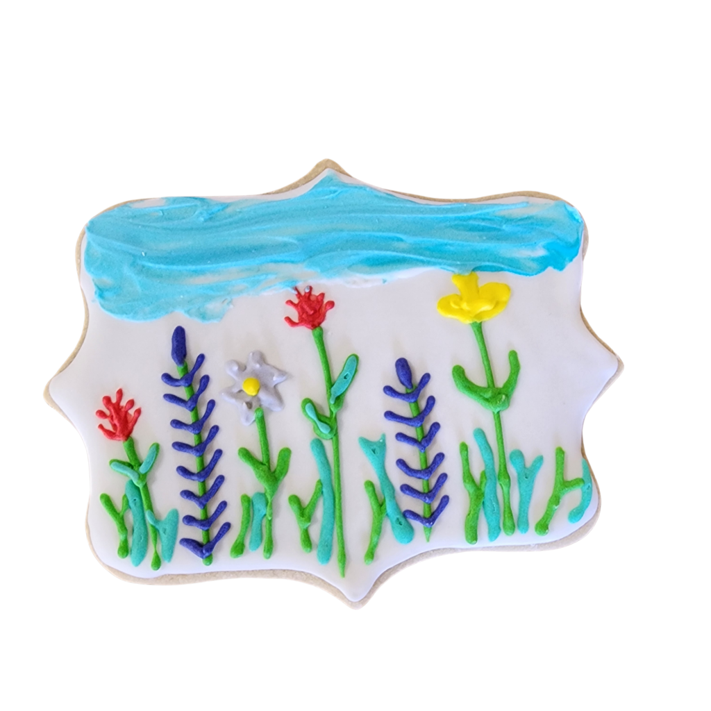 Custom plaque-shaped sugar cookie featuring a hand-painted royal icing garden scene with colorful wildflowers.