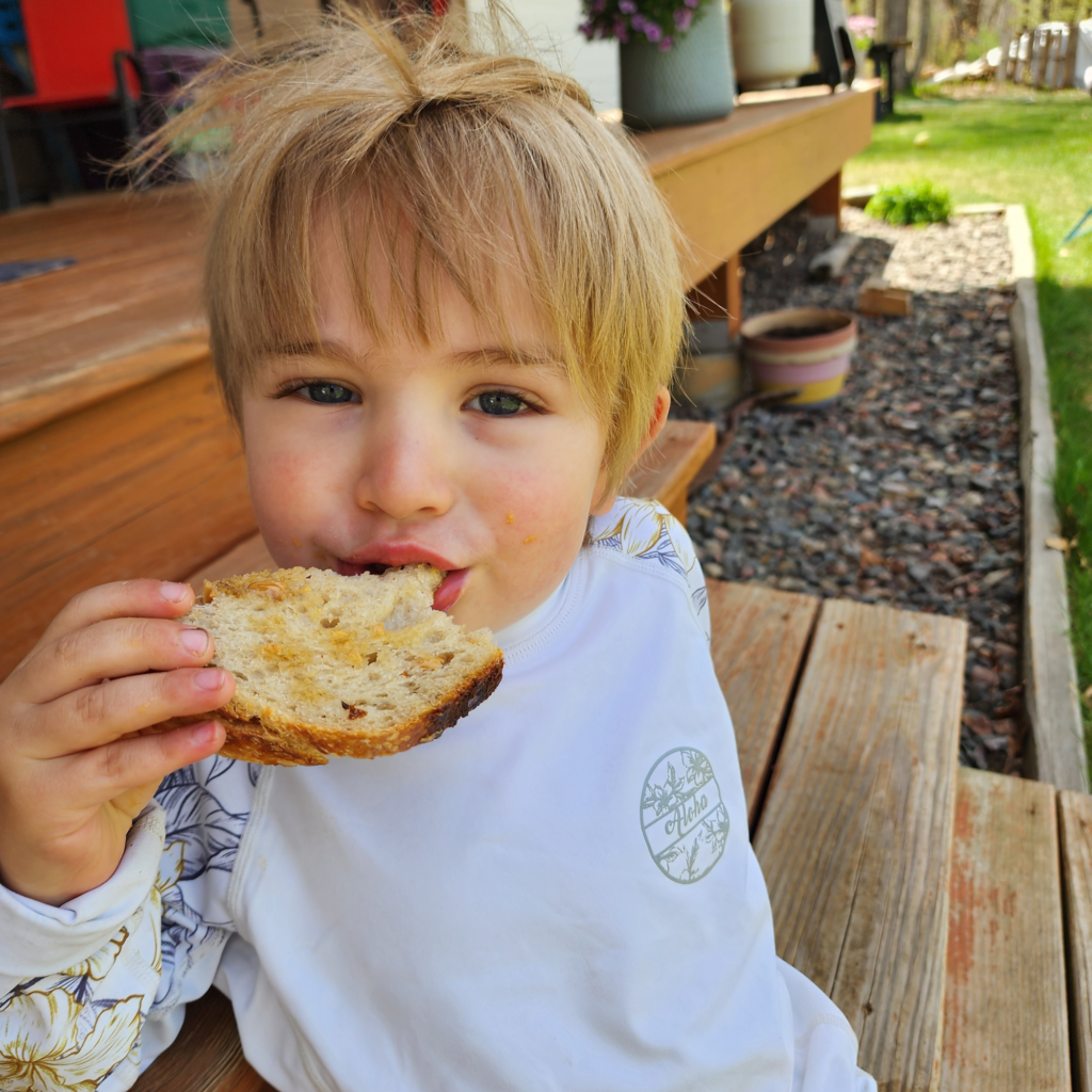 A young child happily enjoying a freshly baked Pioneer Spirit sugar cookie outdoors.