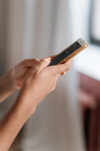 pexels photo 6593754 6593754 A side view close-up of a person's hands using a smartphone with a blurred background.