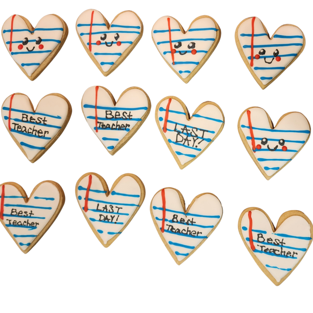 Hand-decorated heart-shaped sugar cookies designed to look like lined notebook paper with text reading 'Best Teacher' and 'Last Day'.